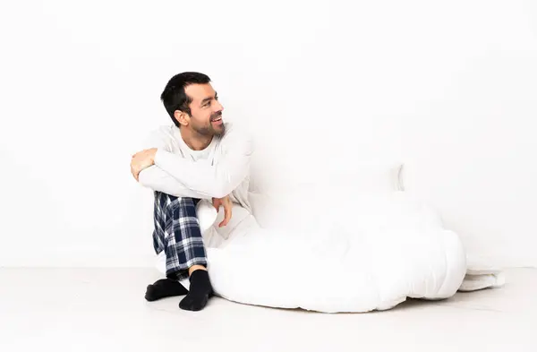 Blanke Man Pyjama Zittend Vloer Binnen Kijkend Naar Zijkant Lachend — Stockfoto