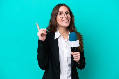 Mavi arka planda izole edilmiş genç bir TV sunucusu harika bir fikre işaret ediyor.