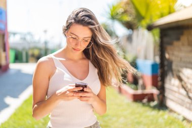 Dışarıdaki güzel bayan cep telefonuyla mesaj yolluyor.