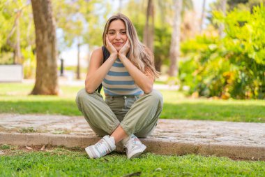 Genç, güzel bir kadın açık havada, mutlu bir ifadeyle.