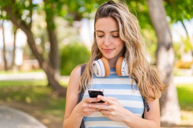 Dışarıda cep telefonu kullanan genç ve güzel bir kadın.