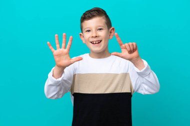 Küçük çocuk mavi arka planda izole edilmiş yediyi parmaklarıyla sayıyor