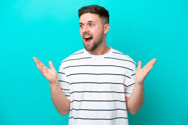 Mavi arka planda yalıtılmış beyaz bir adam. Şaşırtıcı bir yüz ifadesi var.