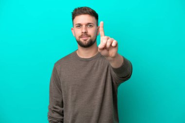 Kafkasyalı genç adam mavi arka planda izole edilmiş ciddi bir ifadeye sahip birini sayıyor.
