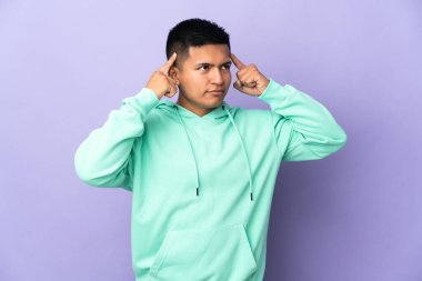 Genç Ekvadorlu adam mor arka planda izole edilmiş. Şüpheleri ve düşünceleri var.