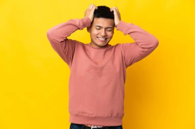 Genç Ekvadorlu adam sarı arka planda izole edilmiş gülüyor.