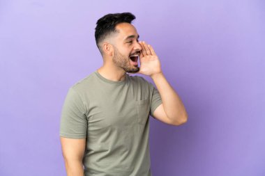 Mor arka planda izole edilmiş genç beyaz adam ağzı sonuna kadar açık bağırıyor.