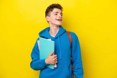 Genç Rus öğrenci, sarı arka planda izole bir şekilde gülüyor.