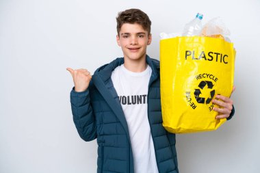 Beyaz arka planda geri dönüşüm yapmak için elinde plastik şişelerle dolu bir çanta tutan genç Rus bir ürünü sunmak için kenarı işaret ediyor.