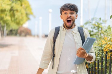 Genç Arap öğrenci şaşırmış ve şok olmuş bir yüz ifadesiyle dışarıda bekliyor.