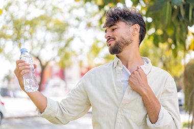 Açık havada bir şişe suyu olan genç Arap yakışıklı bir adam.