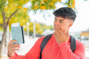 Dışarıda pasaport tutan genç İspanyol bir adam şaşırmış ve şok olmuş bir yüz ifadesiyle.