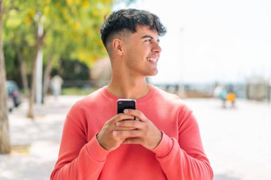 Dışarda cep telefonu kullanan genç bir İspanyol.