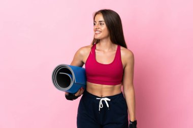 Genç Uruguaylı kadın pembe arka planda bir paspas ile izole edilmiş ve gülümsüyor.