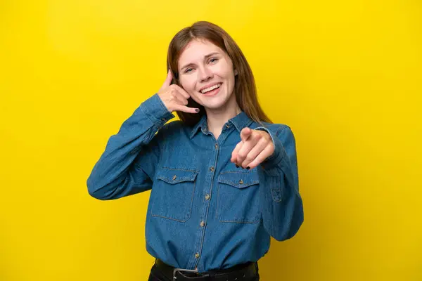 Young English woman isolated on yellow background making phone gesture and pointing front