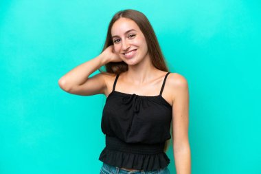 Mavi arka planda izole edilmiş genç beyaz kadın gülüyor.