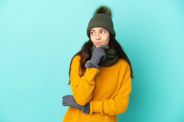 Mavi arka planda izole edilmiş genç bir Fransız kız, kış şapkası kuşkulu.