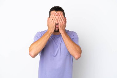 Beyaz arka planda izole edilmiş yakışıklı beyaz adam gözleri elleriyle kapatıyor.