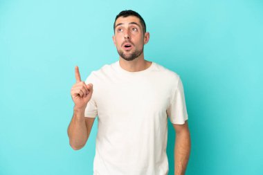 Genç, beyaz, mavi arka planda izole edilmiş genç bir adam bir fikir düşünüyor.