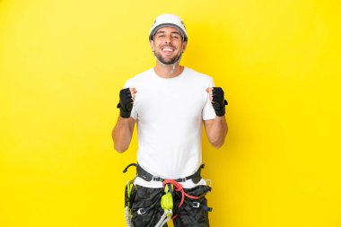 Genç kaya tırmanışçısı sarı arka planda tek başına zaferi kutluyor.