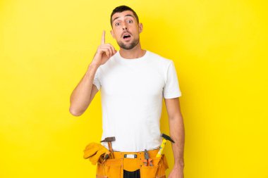 Genç elektrikçi beyaz adam sarı arka planda izole edilmiş.