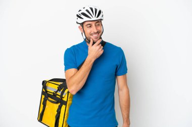 Beyaz arka planda izole edilmiş termal sırt çantalı beyaz bir adam yana bakıyor ve gülümsüyor.