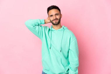 Pembe arka planda izole edilmiş genç beyaz bir adam hayal kırıklığı ifadesi ve anlamama.