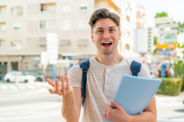Yüzünde şok ifadesi olan genç ve yakışıklı bir öğrenci.
