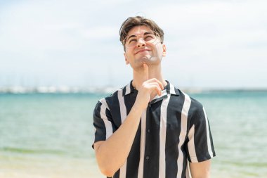 Gözlüklü ve yukarı bakan genç yakışıklı adam.