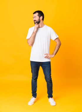 Sakallı, izole edilmiş sarı arka planı olan bir adamın tam boy fotoğrafı.