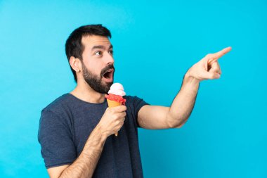 Kornet dondurması ve izole edilmiş mavi arka planı olan genç bir adam.