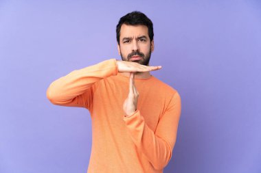 Mor arka planda, beyaz, yakışıklı bir adam zaman aşımı hareketi yapıyor.