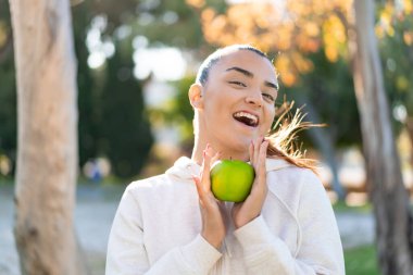 Elma tutan genç ve güzel bir bayan. Şaşırmış bir ifade.