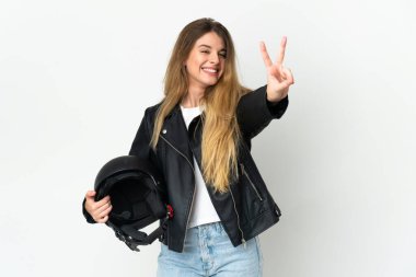 Beyaz arka planda izole edilmiş motosiklet kaskı tutan kadın gülümsüyor ve zafer işareti gösteriyor.