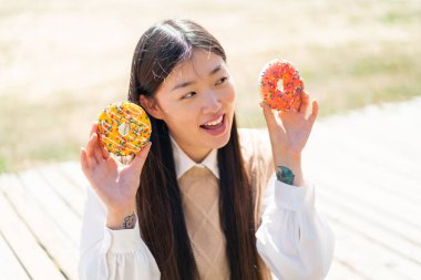 Dışarıdaki genç Çinli kadın elinde donutlarla şaşırdı.