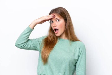Beyaz arka planda izole edilmiş genç beyaz kadın yan tarafa bakarken sürpriz jest yapıyor.