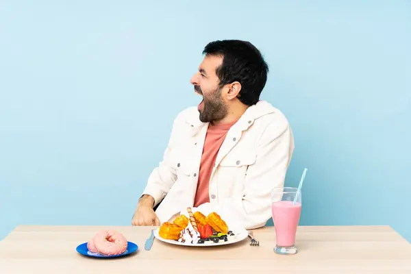 Man Vid Ett Bord Med Frukostvåfflor Och Milkshake Skrattar Sidoläge — Stockfoto