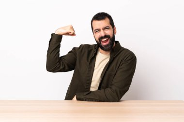 Masada sakallı beyaz bir adam güçlü bir jest yapıyor..