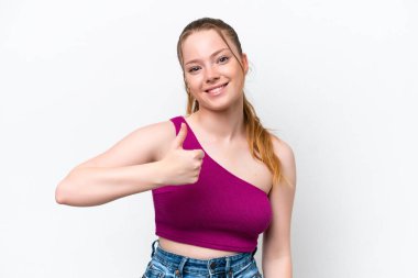 Beyaz arka planda izole edilmiş genç beyaz bir kız baş parmak hareketi yapıyor.