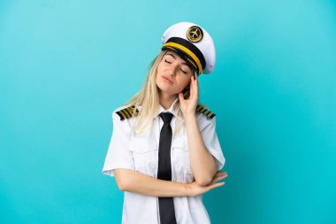 Uçak pilotu mavi arka planda, baş ağrısı var.