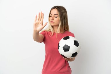 Genç futbolcu kadın, izole edilmiş beyaz duvarda durup jest yapıyor ve hayal kırıklığına uğruyor.