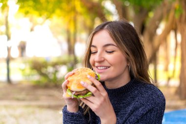 Genç ve güzel Romen kadın elinde hamburgerle