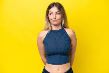 Sarı arka planda izole edilmiş genç Romen kadın şüpheli hareketler yapıyor.