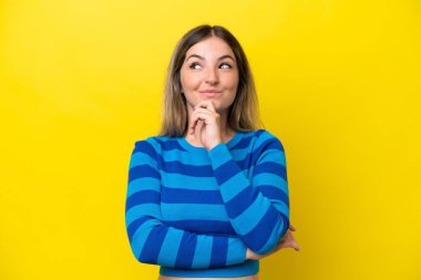 Young Rumanian woman isolated on yellow background thinking an idea while looking up clipart