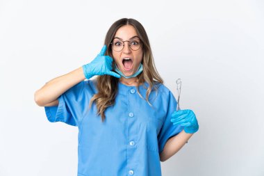 Pembe arka planda izole edilmiş aletleri elinde tutan Romen kadın diş hekimi telefon jesti yapıyor. Bana geri dönüş işareti ver.