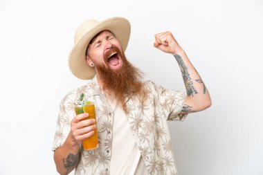 Uzun sakallı, kumsalda kokteyl içen kızıl saçlı bir adam zaferi kutluyor.