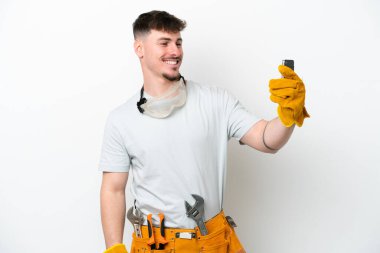 Beyaz arka planda izole edilmiş beyaz tenli elektrikçi selfie çekiyor.