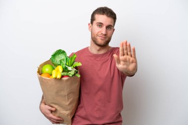 Beyaz arka planda izole edilmiş alışveriş torbası tutan beyaz bir adam dur hareketi yapıyor.