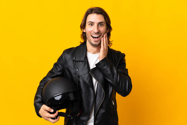 Man with a motorcycle helmet isolated on yellow background with surprise and shocked facial expression