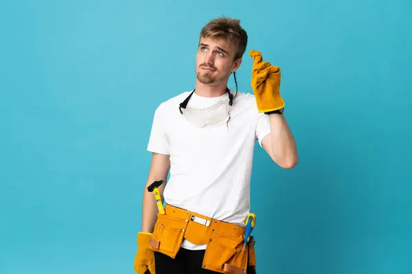Jovem Eletricista Homem Sobre Parede Isolada Com Dedos Cruzando Desejando — Fotografia de Stock